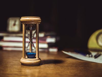 Close up of a wooden hourglass on a dark desk